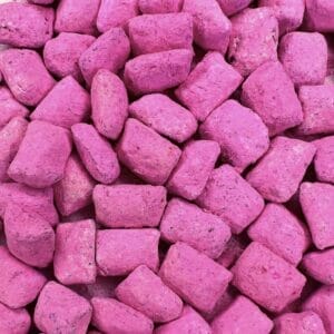 Ein Haufen rosafarbener Steine mit dem Duft von Weihrauch Griechischer Rose auf einer weißen Oberfläche.