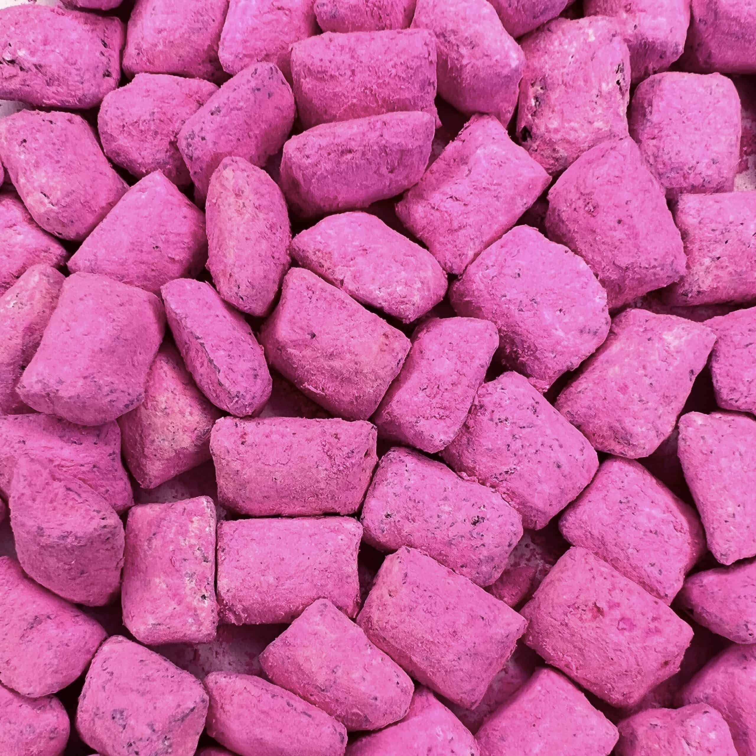 Ein Haufen rosafarbener Steine mit dem Duft von Weihrauch Griechischer Rose auf einer weißen Oberfläche.