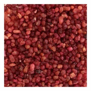 Ein Haufen roter Samen auf weißem Hintergrund mit griechischem Flieder Weihrauch.