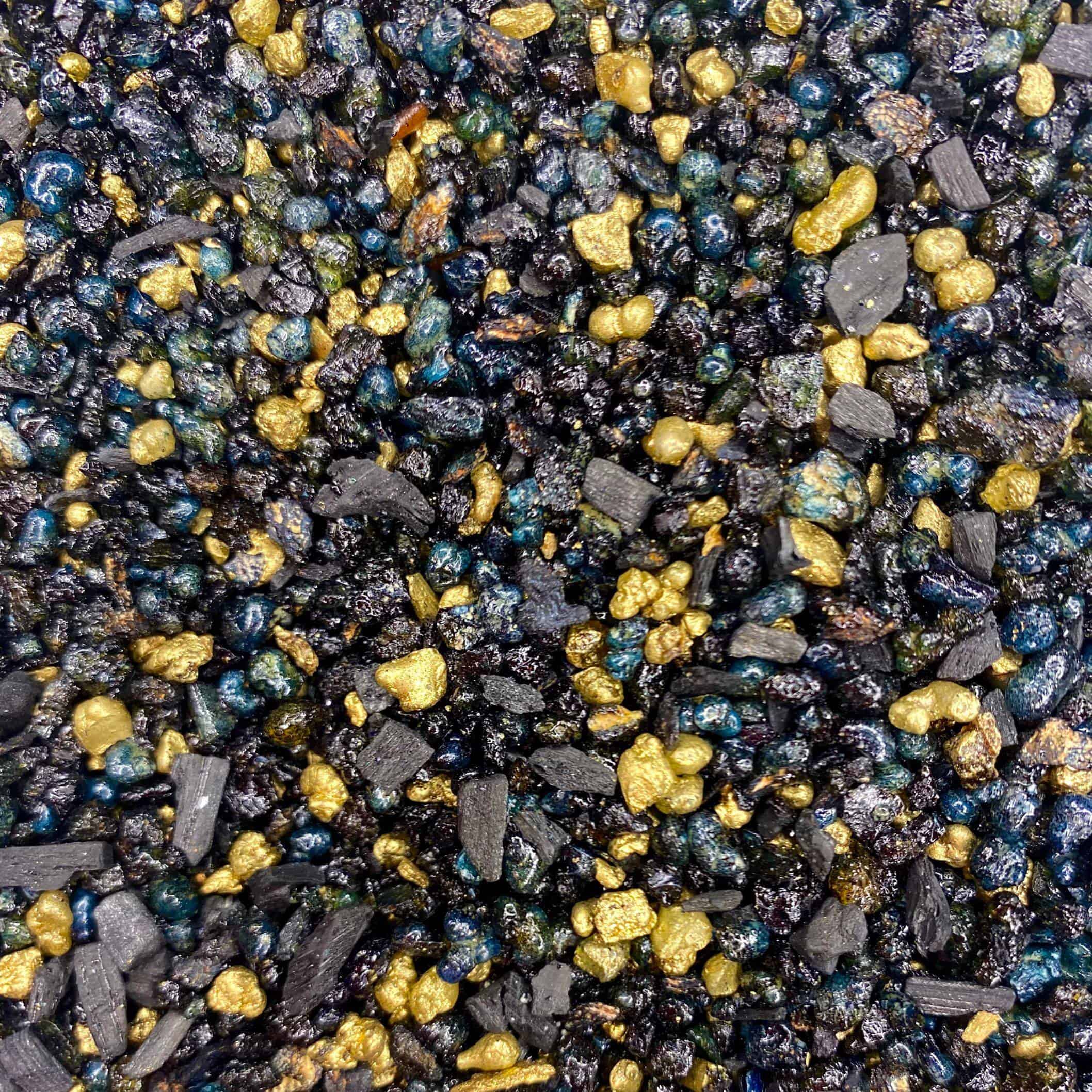 Eine Nahaufnahme eines Haufens aus schwarzem, gelbem und blauem Kies, der zum Schutz mit Weihrauchharz Protection durchtränkt ist.