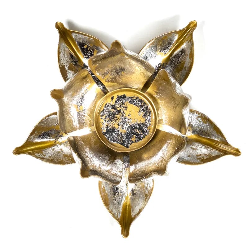 Ein goldener, blütenförmiger Kerzenhalter auf einer weißen Oberfläche.