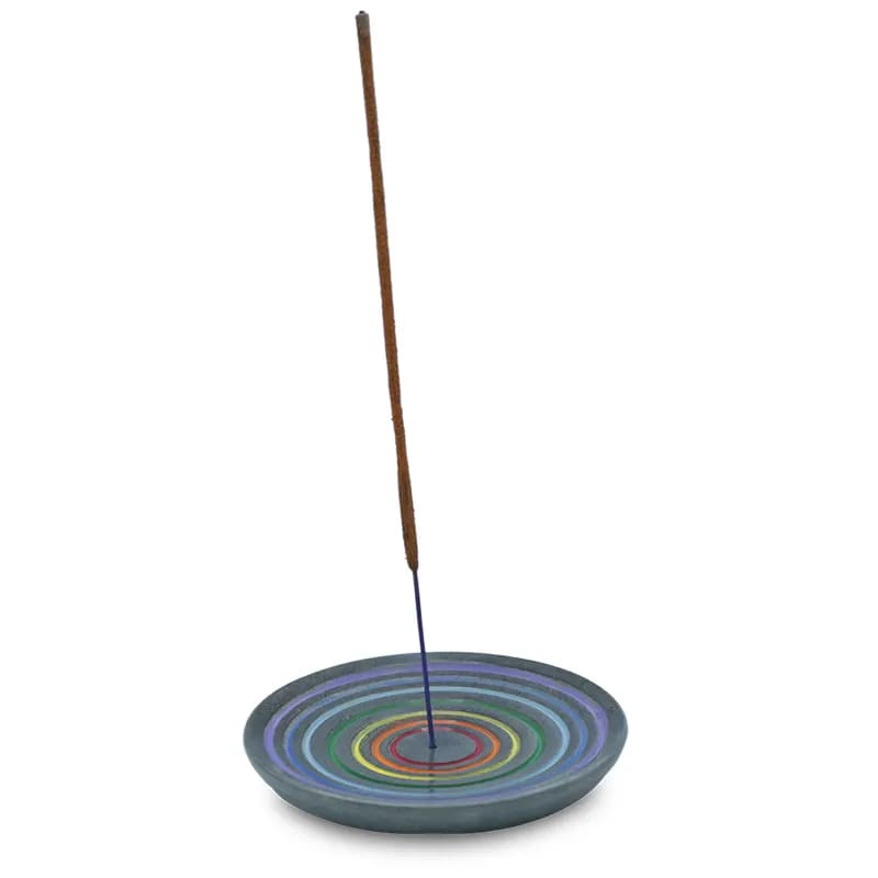 Ein bunter Weihrauchbrenner auf einem Teller mit einem Holzstab.